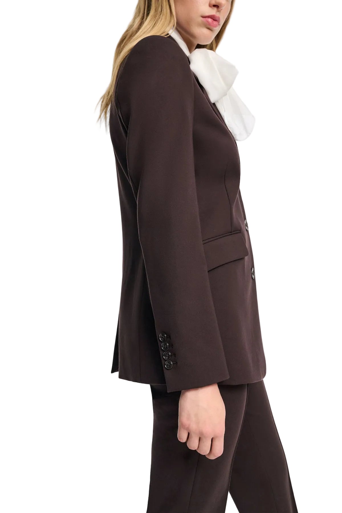 A person is shown from the side wearing the Dorothee Schumacher Emotional Essence Jacket in espresso with notch lapel and matching pants, paired with a large white bow tie.