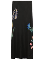 The Seductive Bloom Skirt by Dorothee Schumacher features a black bias cut accented with subtle blue, purple, and pink floral embroidery on the front.