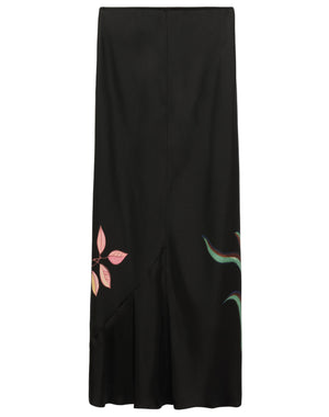 The Seductive Bloom Skirt by Dorothee Schumacher is a black bias-cut skirt with a straight silhouette, featuring a pink leaf on the left and a green abstract motif on the right.