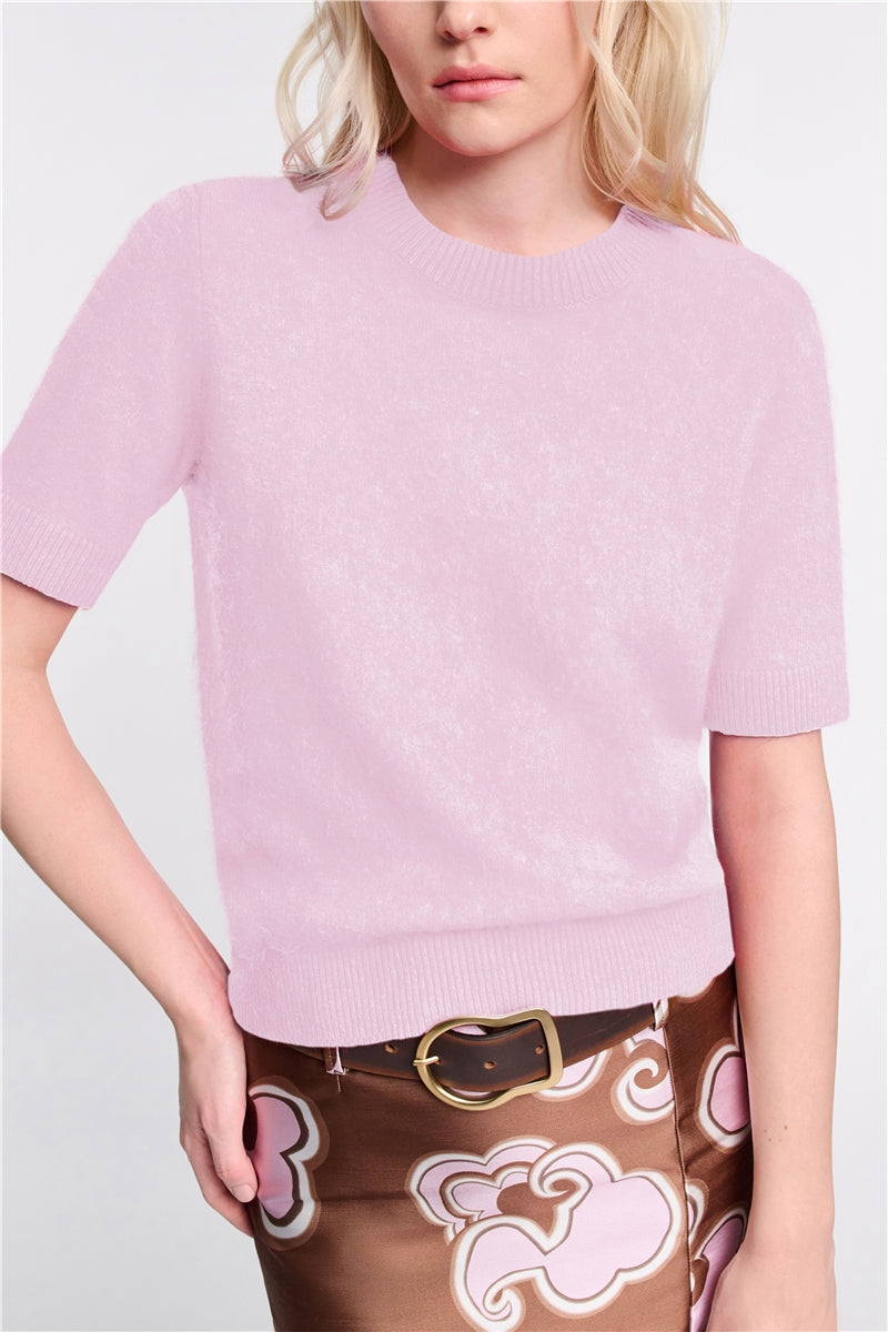 A person wearing the Dorothee Schumacher Fluffy Statements Pullover in light pink cashmere-Merino wool, styled with a brown skirt featuring a pink and white abstract pattern and a black belt.