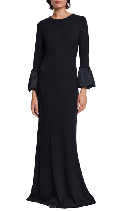 A woman wears the Dorothee Schumacher Cloudy Allure Dress, a long black midi made from wrinkle-free travel jersey with satin bubble cuffs, posed against a white background.