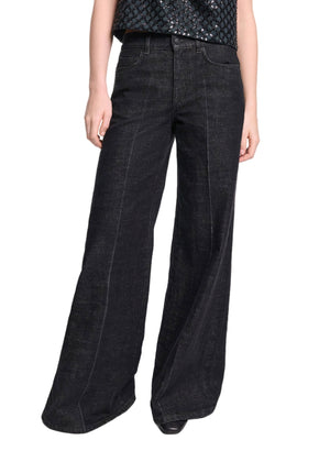 Model wears the Deep Love Pants by Dorothee Schumacher—wide-leg, dark wash black jeans—paired with a textured black top, set against a white background.