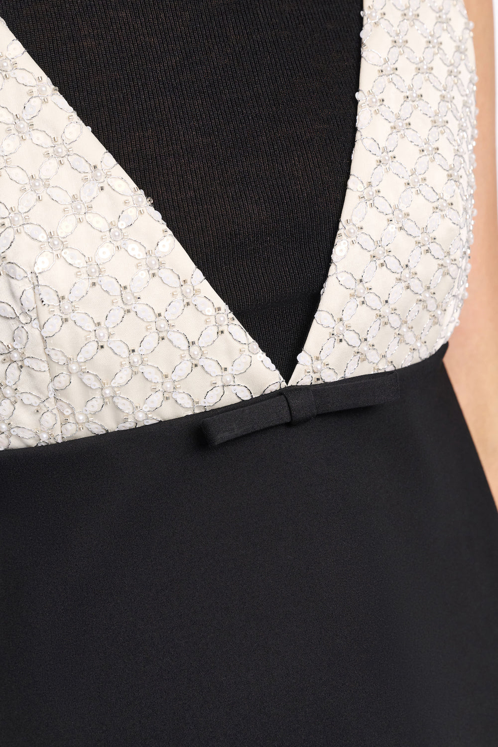 Close-up of the Dorothee Schumacher Emotional Essence Dress featuring a textured white and black geometric bodice, deep V-neckline, and a small black bow at the waist.