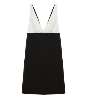 The Emotional Essence Dress by Dorothee Schumacher features a sleeveless V-neck, a white textured bodice, solid black skirt, and a small black bow at the waist.