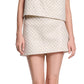A person is shown from mid-torso to mid-thigh wearing the Sparkling Statement Mini Skirt by Dorothee Schumacher, paired with a sleeveless, light-colored, patterned top.