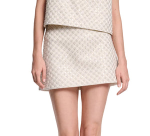 A person is shown from mid-torso to mid-thigh wearing the Sparkling Statement Mini Skirt by Dorothee Schumacher, paired with a sleeveless, light-colored, patterned top.