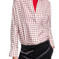 Person wearing the Dorothee Schumacher Graphic Dreams Blouse, a white patterned button-up, layered over a red turtleneck and styled with black pants. Hands are in pockets.