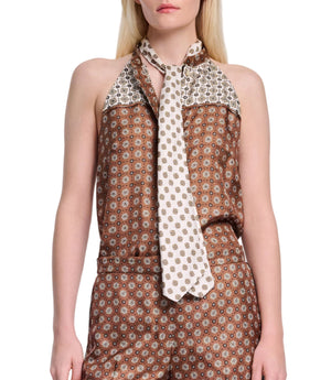 A woman wears the Dorothee Schumacher Graphic Dreams Top, a brown patterned silk twill sleeveless piece with a white tie, paired with matching high-waisted pants featuring signature prints, standing against a plain background.