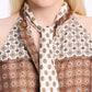 A person is seen in the Graphic Dreams Top by Dorothee Schumacher—brown and cream with signature prints—paired with a matching patterned necktie. Their face is partially visible.