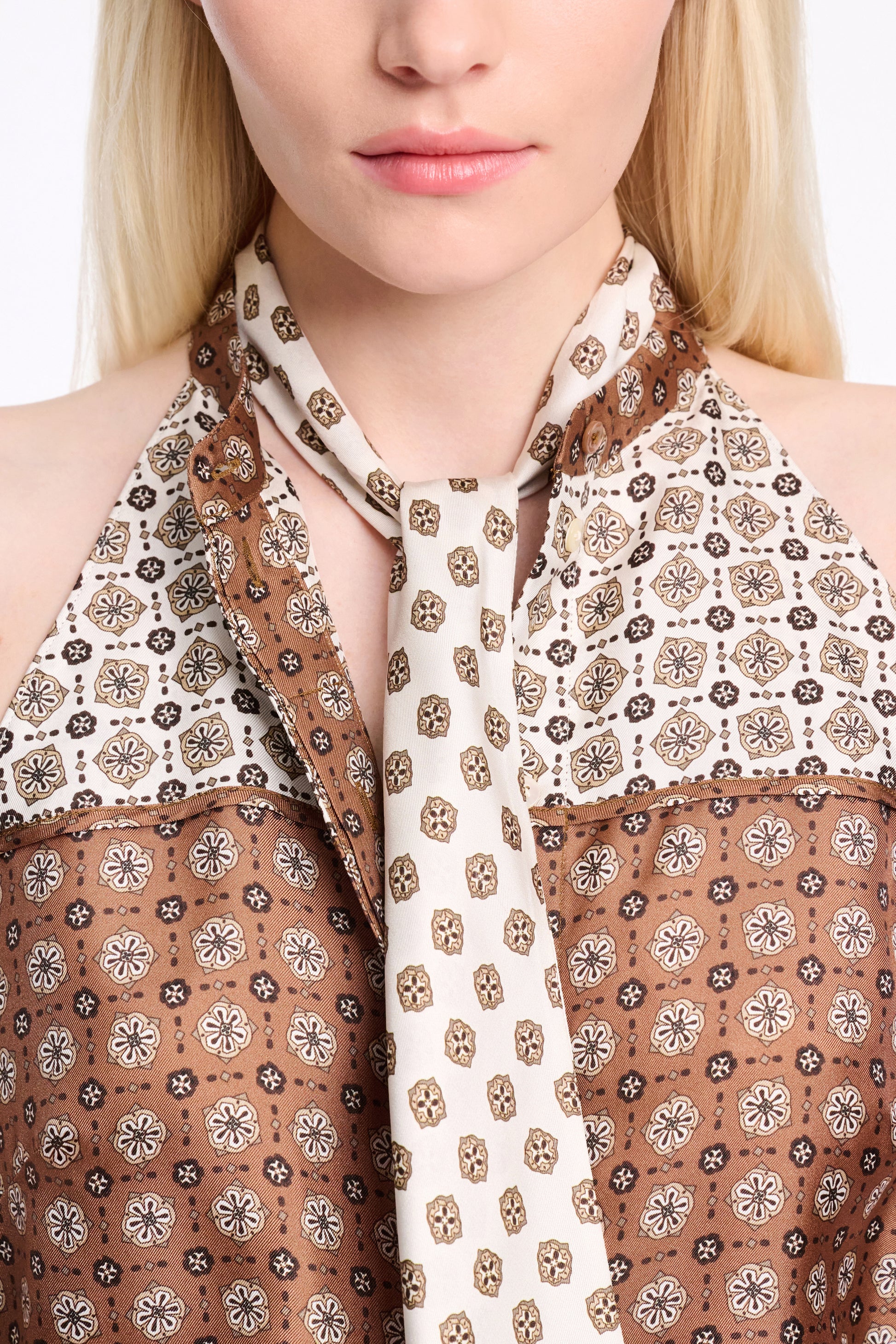 A person is seen in the Graphic Dreams Top by Dorothee Schumacher—brown and cream with signature prints—paired with a matching patterned necktie. Their face is partially visible.