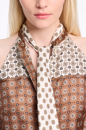 A person is seen in the Graphic Dreams Top by Dorothee Schumacher—brown and cream with signature prints—paired with a matching patterned necktie. Their face is partially visible.