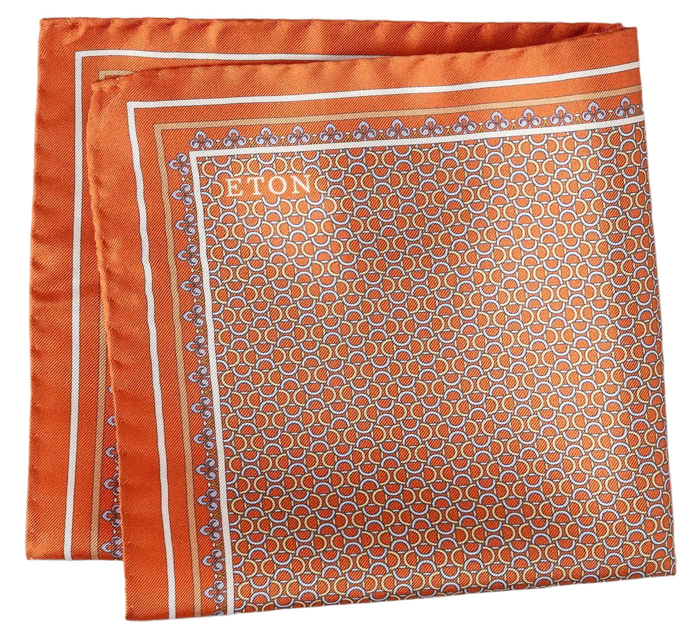 The Geometric Silk Twill Pocket Square by Eton features an orange patterned silk twill fabric, accented with a white border and a repeating hexagonal geometric motif. The elegantly printed brand name "Eton" appears in white on one corner.