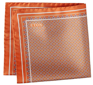 The Geometric Silk Twill Pocket Square by Eton features an orange patterned silk twill fabric, accented with a white border and a repeating hexagonal geometric motif. The elegantly printed brand name "Eton" appears in white on one corner.