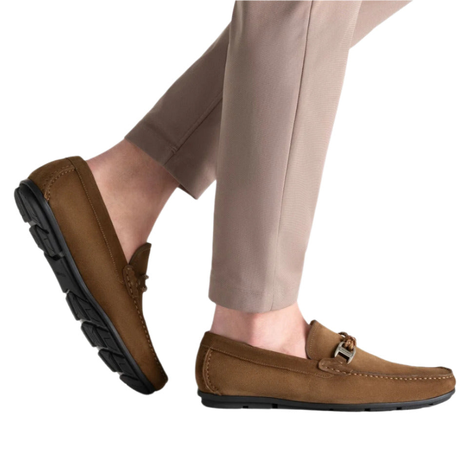 The Monterey Braid Bit Driver Loafers by Magnanni feature a supple calfskin upper, styled with beige pants against a crisp white backdrop. Inspired by traditional driving shoes, their metal buckle detail adds classic elegance to the ensemble.