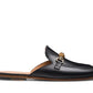 The Sienna Luck II Mule by Magnanni is a black leather slip-on loafer featuring a rounded toe, gold horsebit accent, and flat tan sole.