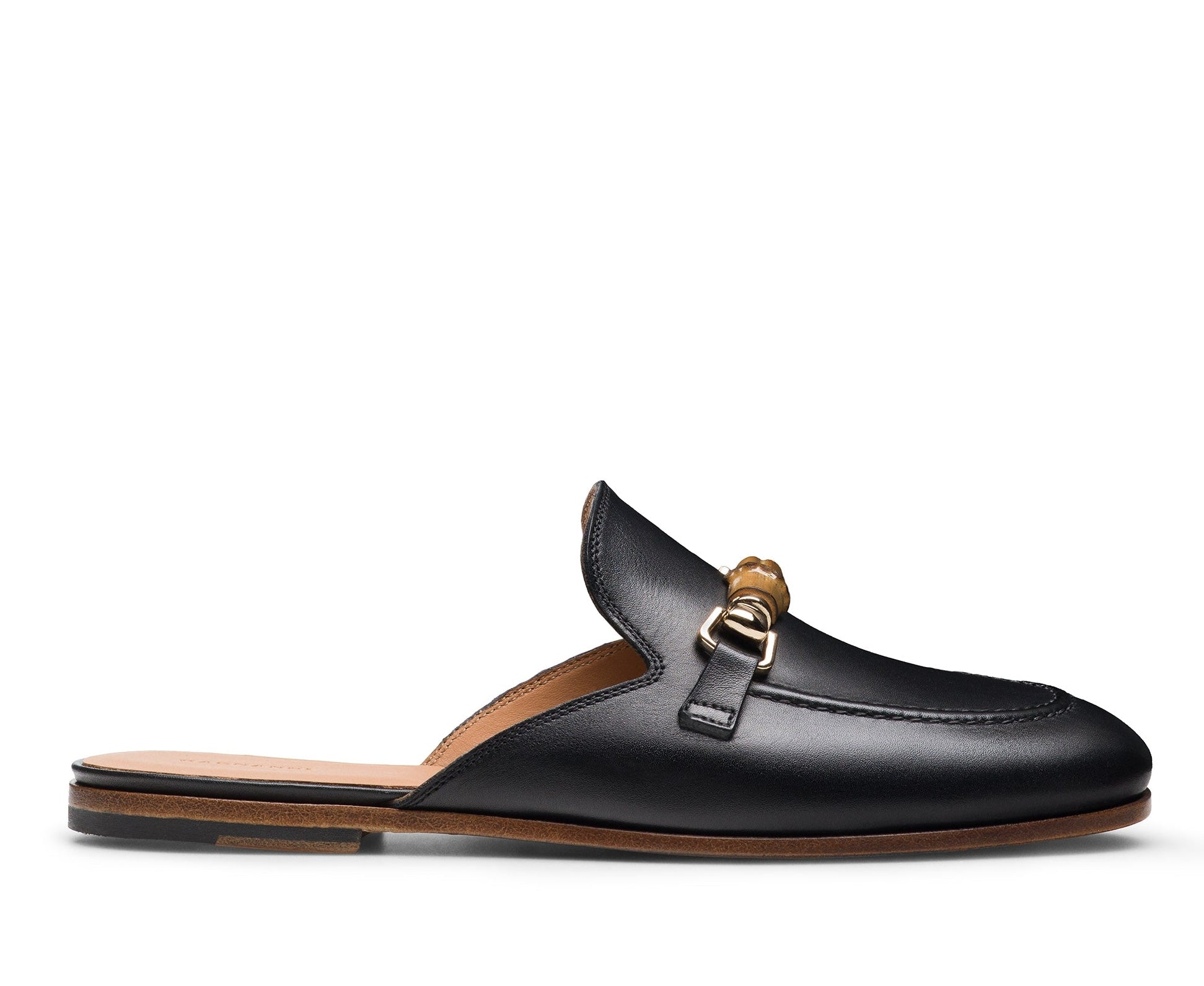 The Sienna Luck II Mule by Magnanni is a black leather slip-on loafer featuring a rounded toe, gold horsebit accent, and flat tan sole.