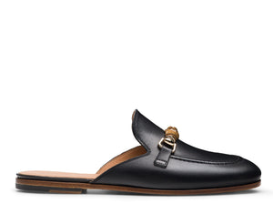 The Sienna Luck II Mule by Magnanni is a black leather slip-on loafer featuring a rounded toe, gold horsebit accent, and flat tan sole.
