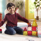 A young boy sits on the floor, smiling as he plays imaginatively with the Magnatiles Fire Rescue 27-Piece Set and a toy car in a brightly lit living room.