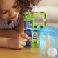 A child sits at a wooden table and plays with the Magnatiles Hamster Ball 13-Piece Set, placing a small animal figure inside the translucent magnetic building pieces.