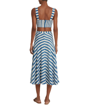 Seen from the back in a blue and white striped crop top with an Emporio Sirenuse Marta Ikat Stripe Skirt, the handloom cotton attire is perfect for warm weather. The plain background enhances the elegance of its Ikat Stripes print.