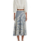 A person is shown from the back wearing a white cropped blouse with the elegant Emporio Sirenuse Tasha Palm Embroidery Skirt in Japanese linen featuring white leaf patterns, paired with white sandals.