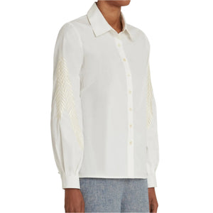 Someone is wearing the Emporio Sirenuse Carolina Palm Embroidery Top with blue jeans. This classic shirt, with a feminine twist, features tonal palm leaf embroidery on the sleeves.