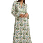 A person wearing the Emporio Sirenuse Jenna Persian Botanic Silk Dress, featuring elegant green and blue floral patterns with graceful bell sleeves, stands against a plain white background.