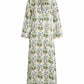 The Emporio Sirenuse Jenna Persian Botanic Silk Dress offers a caftan style with long bell sleeves and a V-neckline, adorned with green botanical patterns on a white backdrop.