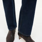 Person wearing dark blue jeans and Staud Wally Woven Leather Ankle Boots with low blade heels, standing on a light background.