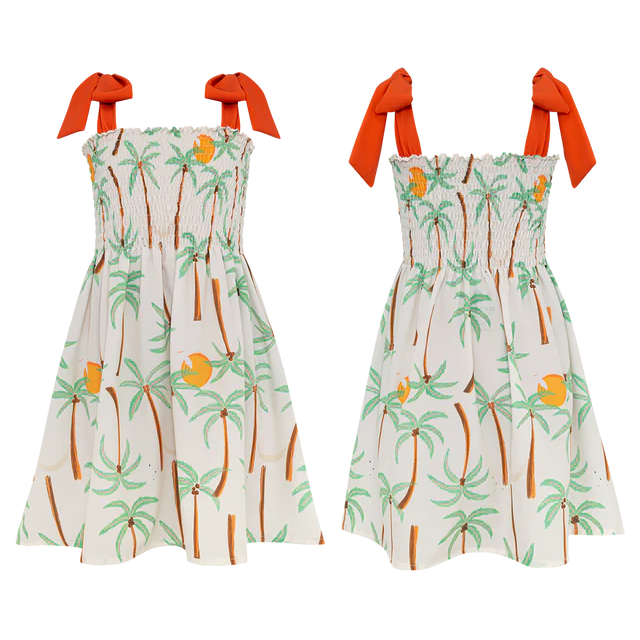 Two sleeveless Pepita & Me Girls' Waffle Dresses with orange shoulder ties feature a tropical palm tree and fruit print on white. The smocked top adds comfort and style—perfect for sunny days. Made in Colombia.