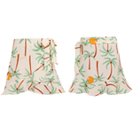 Front and back views of the Pepita & Me Girls' Marea Skirt—a comfy white skirt with palm tree and orange fruit print, side-tied. Perfect summer wear for girls.