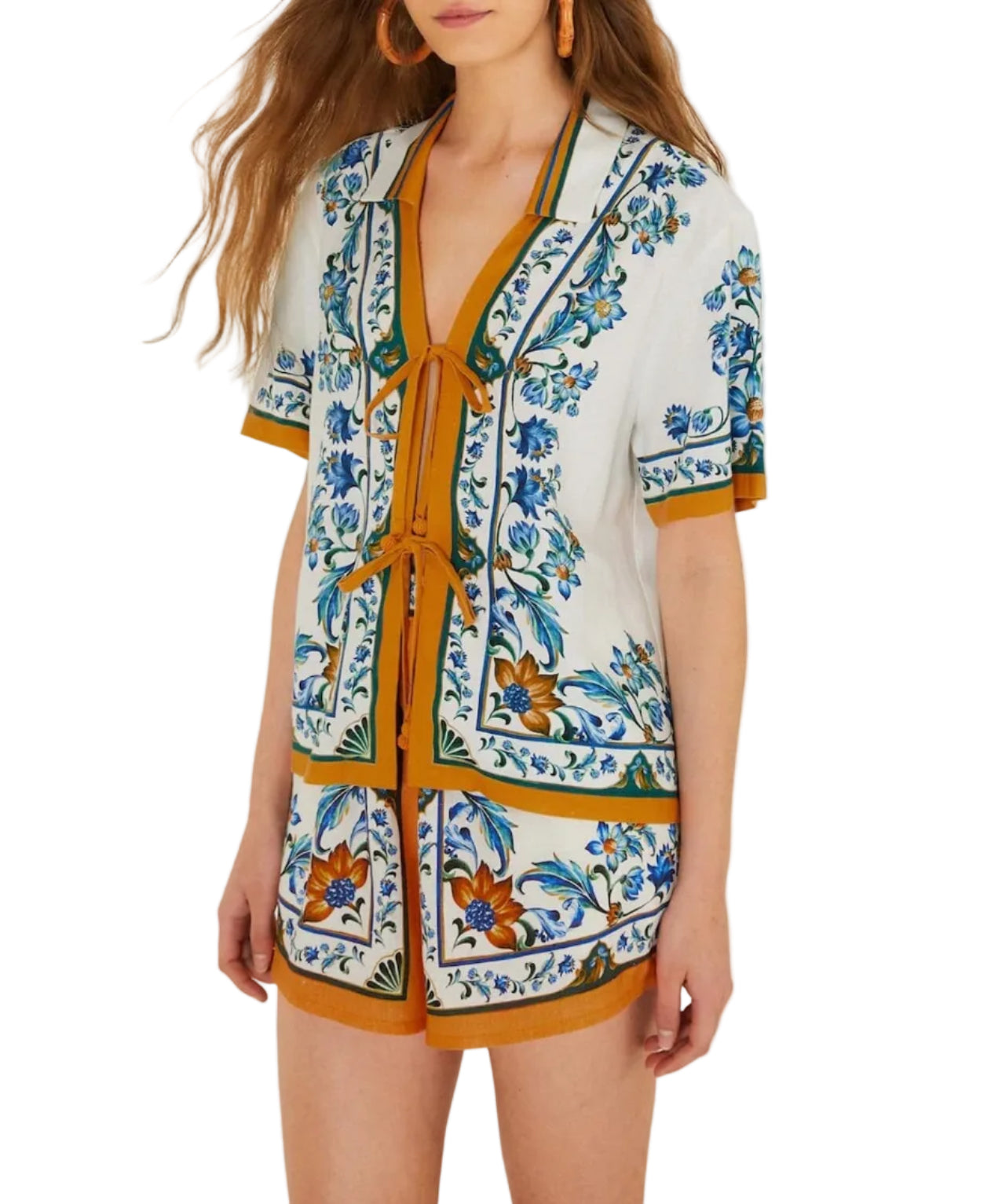 A woman stands against a white background wearing the Farm Rio Flora Tile Off White Blouse with matching floral tile shorts and orange accents.