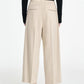 Model wears the Maria McManus Drawstring Trouser, featuring wide-leg, beige cropped loungewear style with an elastic waistband and two back welt pockets, paired with a black long-sleeve top and black shoes, standing against a white background.