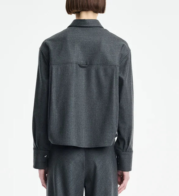 A person stands with their back to the camera, wearing the Maria McManus Button Sleeve Crop Shirt in dark gray wool flannel with a cropped silhouette, paired with matching trousers, set against a plain white background.