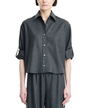 A person wearing the Maria McManus Button Sleeve Crop Shirt in dark gray wool flannel, featuring a cropped silhouette and rolled-up button sleeves, paired with matching wide-leg pants and standing against a plain white background.
