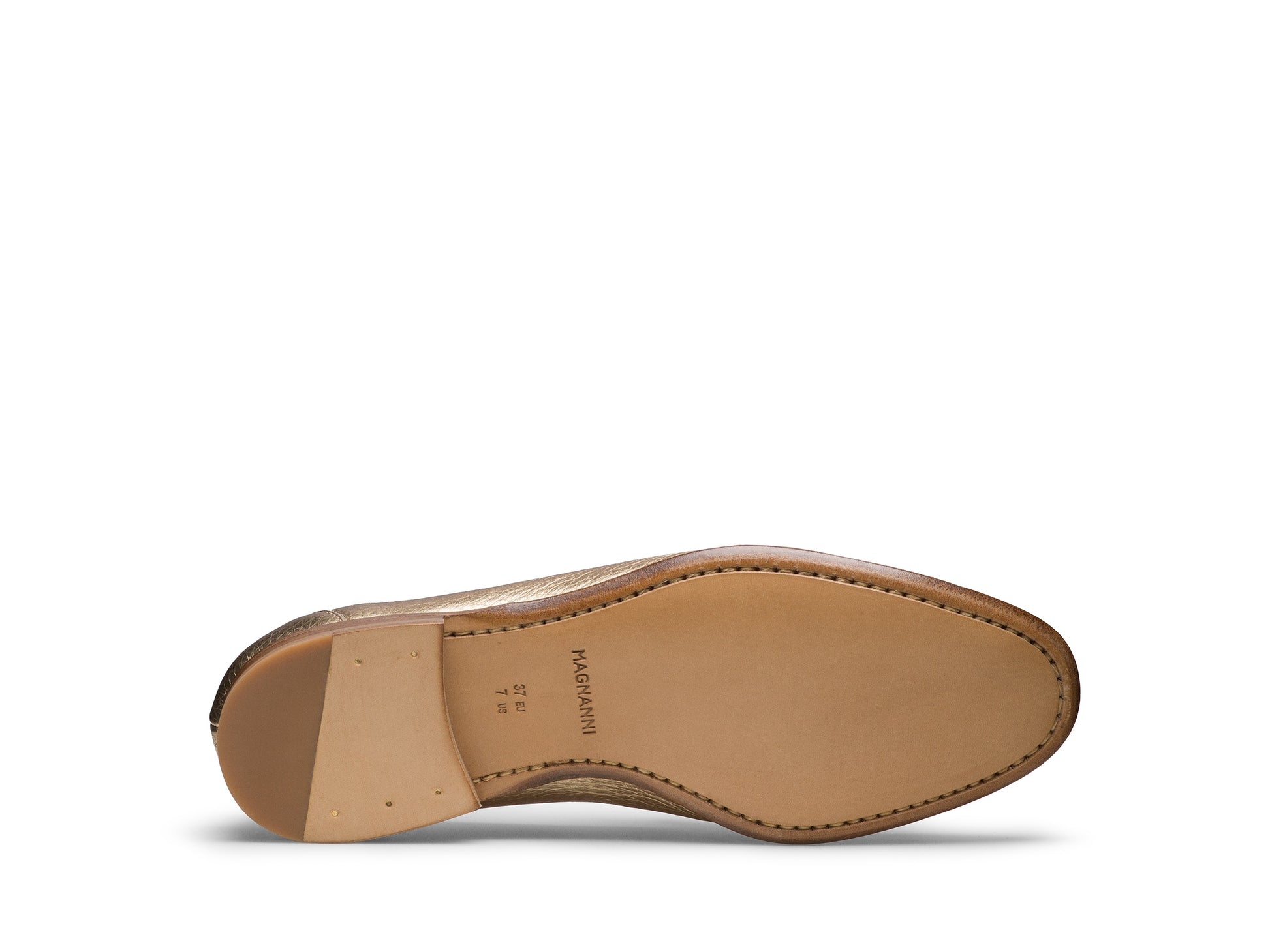 The image shows the sole of the Sonya Metallic Loafer by Magnanni, a tan slip-on crafted from supple leather with edge stitching and the brand name "Magnanni" printed near the heel.