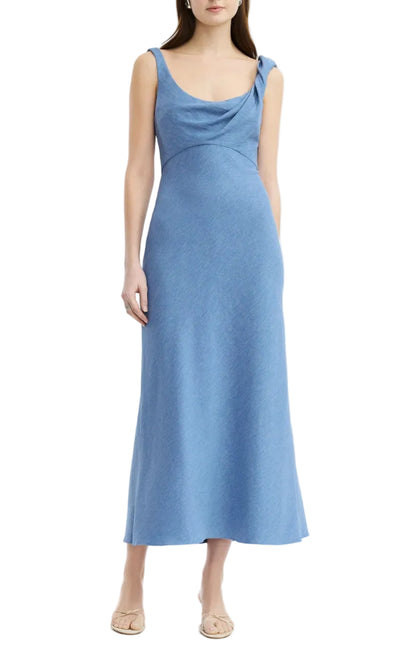 A woman in the Lela Rose Linen Twist Detail Dress—sleeveless, ankle-length, light blue linen with a draped neckline—pairs it with nude flats against a white background.