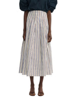 A person wears the Lela Rose Striped Cotton Full Skirt—a high-waisted, ankle-length, blue and white vertically striped piece—paired with a dark top and open-toe sandals for a chic workwear look.