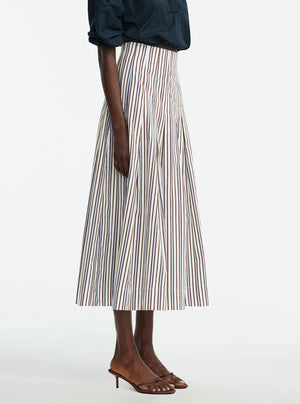 A person wearing a navy blouse, Lela Rose Striped Cotton Full Skirt, and brown heeled sandals stands against a plain background.