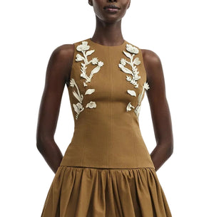A woman models the Lela Rose Leather Floral Embroidered Rustic Top, a sleeveless, fitted brown piece with leather floral embroidery, capturing westernwear elegance against a white background.