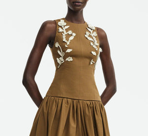 A person wearing the Lela Rose Leather Floral Embroidered Rustic Top, featuring white floral embroidery and a sleeveless brown design, perfect for chic westernwear style.