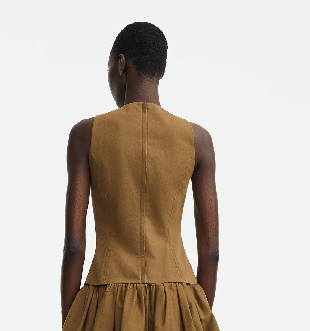 A person stands facing away, wearing the Lela Rose Leather Floral Embroidered Rustic Top against a plain white background.