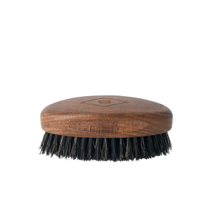 The Barberino's Beard Brush is a small oval brush with a wooden handle and dark natural bristles, ideal for grooming your beard. Shown against a plain white background.