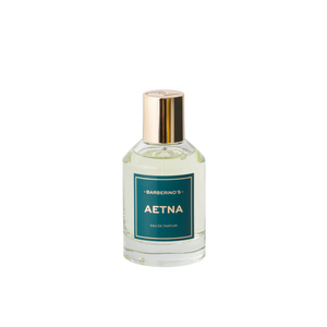 A clear glass bottle of Barberino’s Aetna Perfume Cologne, featuring a green label and gold cap, is photographed against a white background. Inspired by Sicily’s Mount Etna.