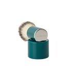 The Barberino's Cruelty Free Shaving Brush features a teal synthetic bristle brush with a cylindrical handle and silver cap, resting upright on a matching teal stand—ideal for a traditional shaving experience.