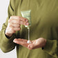 A person in a green shirt squeezes Barberino’s Ultra Hydrating Face Cream, ideal for men's skincare, from a green tube into their palm.