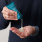 A person dispenses Barberino’s Soothing After Shave Balm, a white cream in a blue tube, onto their palm, ready to boost their grooming routine with deep hydration.