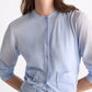 A woman shown from shoulders to hips wears the Dorothee Schumacher Sheer Summer Twinset—a light blue cropped stretch cotton cardigan with two front pockets—paired with light-colored pants.