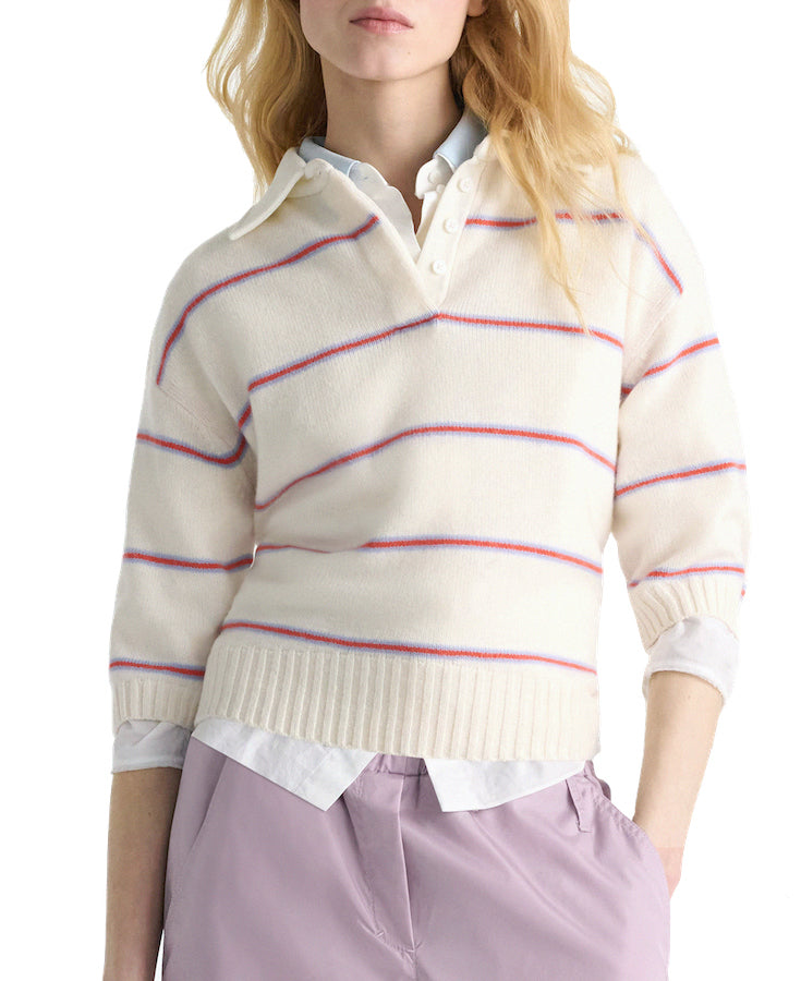 A person models the Dorothee Schumacher Sporty Statements Pullover—a cream Merino-cashmere knit with red and blue stripes—layered over a white collared shirt and paired with light purple pants, set against a white background.