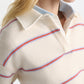 A person wears the Sporty Statements Pullover by Dorothee Schumacher, a cream Merino-cashmere knit with blue and red stripes, layered over a collared shirt for a cropped, boxy look.